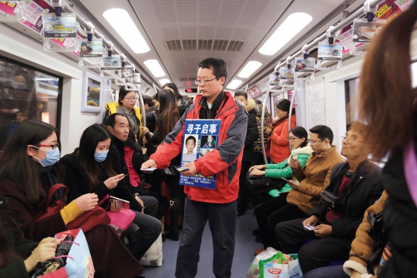 在北京地铁2号线上，陈新刚向乘客发放寻子名片